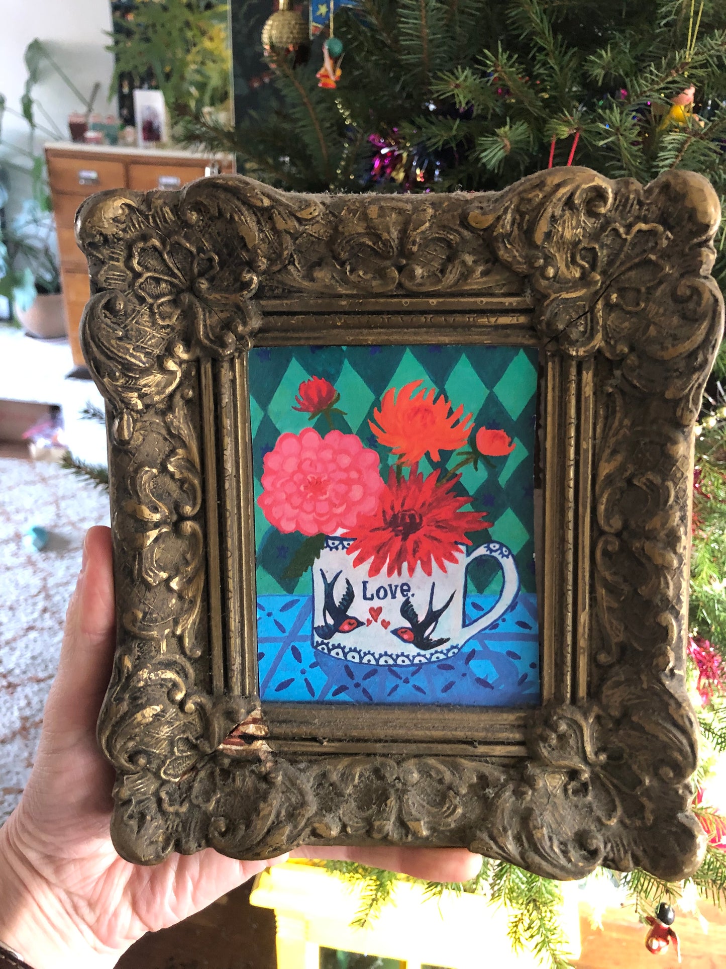 Hippe vrolijke dahlia kaart met de tekst love, liefs en liefde. Op het theekopje met bloemen staan twee zwaluwen met hartjes. Dit kleurrijke duurzame eco kaartje is ook geschikt als valentijnskaart. op de achtergrond van deze ansichtkaart staat een groen ruitenpatroon.